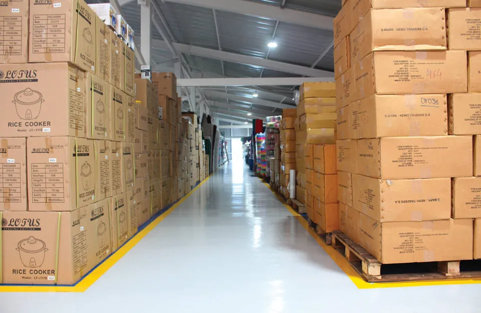 Pasillo de bodega con cajas de mercadería en tarimas