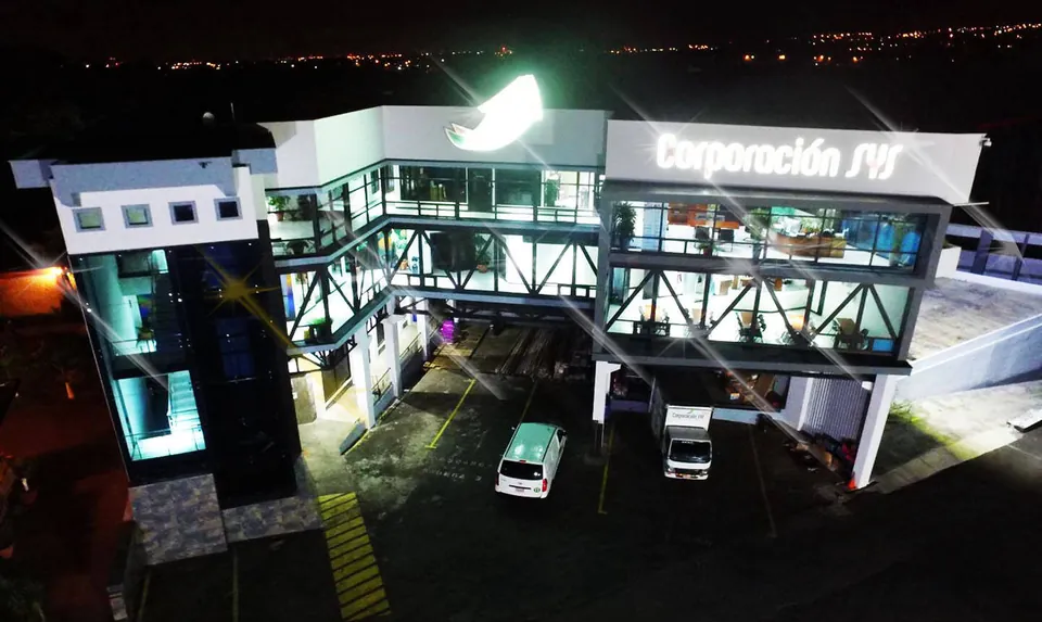 Edificio de Corporación SYS de noche, con el rótulo iluminado